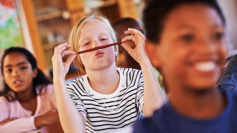 Bored girl in a classroom playing with pencil