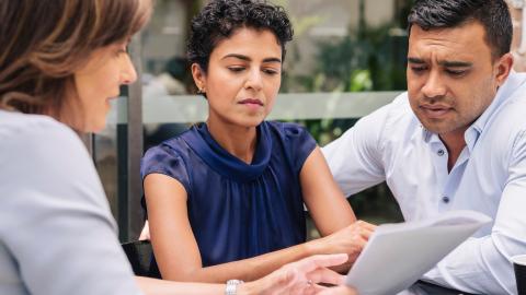 Couple discussing paperwork with woman
