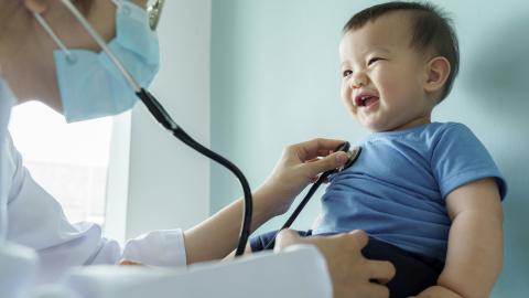 Doctor examines a smiling baby