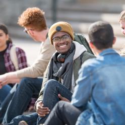 A group of college students sitting on the steps outside
