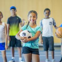 A group of kids all holding different sports balls