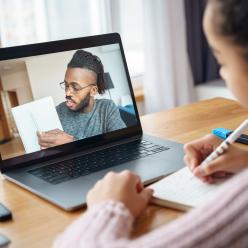 Man on the computer helping a young student with her school work.