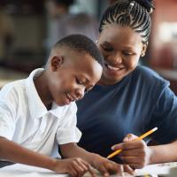 Smiling mother teaching her smiling son at a table