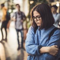 Sad girl standing alone in a school hallway.