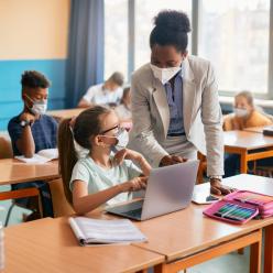 Teacher helping a girl on a laptop in the classroom